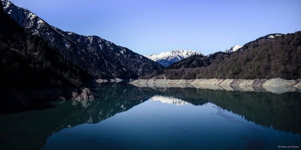 Scenic view of lake and mountains against clear blue sky