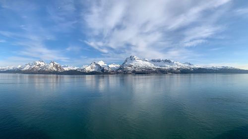 Scenic view of lake by snowcapped mountains against sky