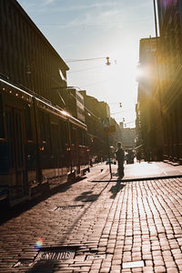 Man walking on street in city against sky