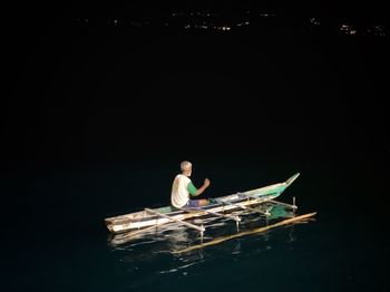 Man sitting on boat against sea