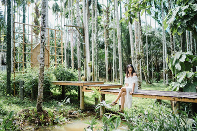 Woman sitting on seat in forest