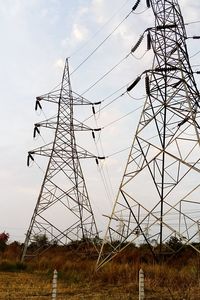 Low angle view of electricity pylon on field