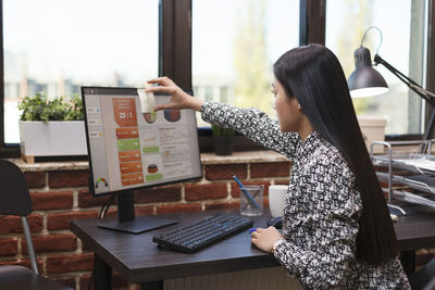 Side view of woman using laptop while sitting on table
