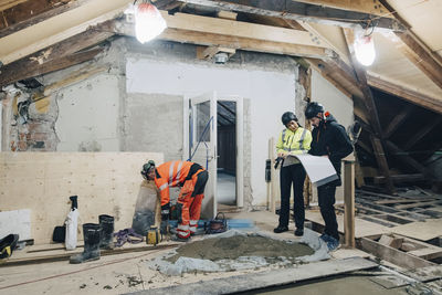 Full length of female building contractor discussing with male worker at site