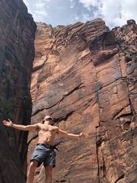 Low angle view of shirtless man standing against cliff