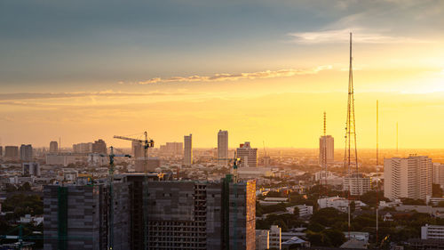 Modern buildings in city against sky during sunset