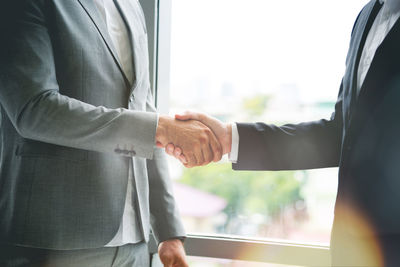 Midsection of business people shaking hands