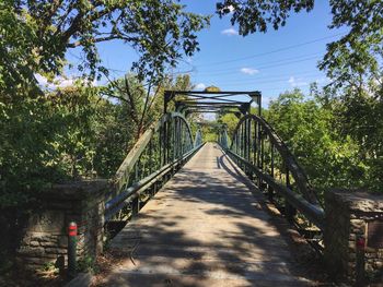 Footbridge amidst trees against sky