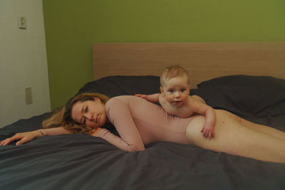 Portrait of mother and baby boy lying on bed
