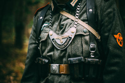 Midsection of person holding camera while standing against wall