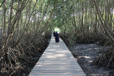 Rear view of woman amidst trees in forest