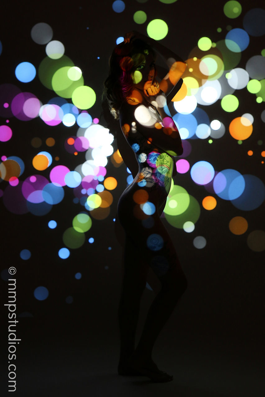 illuminated, one person, glowing, real people, night, standing, multi colored, full length, lighting equipment, indoors, lifestyles, women, adult, leisure activity, light - natural phenomenon, celebration, light, lens flare, defocused