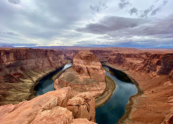 Scenic view of horseshoe bend rock formation against cloudy sky