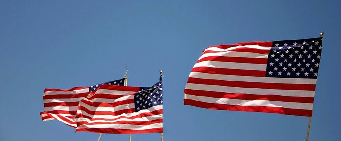 Low angle view of american flags against clear sky