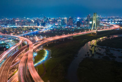 High angle view of illuminated light trails on road amidst buildings in city at night