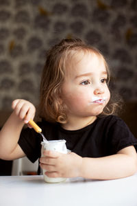 Cute girl eating curd at home