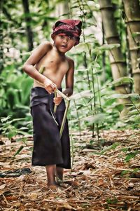 Full length of shirtless boy looking at camera