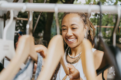 Happy woman hanging dress on clothes rack at flea market