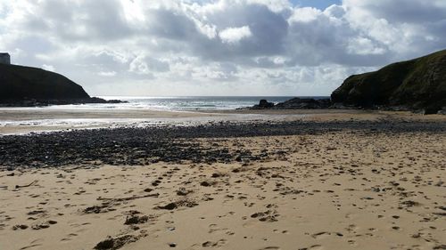 Scenic view of beach against cloudy sky