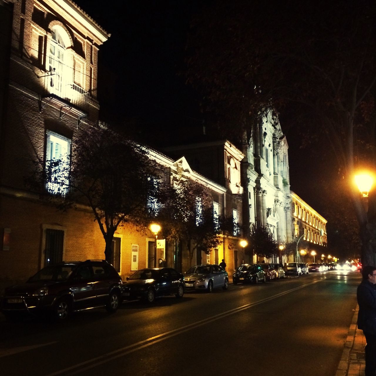 illuminated, night, building exterior, car, transportation, street, architecture, land vehicle, built structure, road, city, mode of transport, city street, street light, city life, traffic, road marking, incidental people, the way forward, outdoors