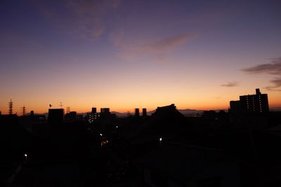 Silhouette cityscape against dramatic sky during sunset