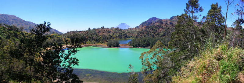 Scenic view of lake and mountains against clear blue sky