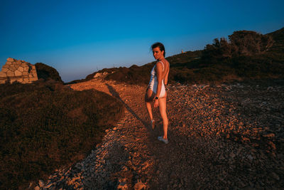 Portrait of young woman standing on land against sky