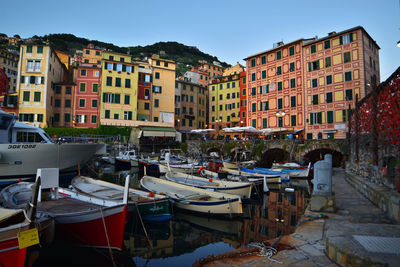 Boats moored in canal amidst buildings in city against sky