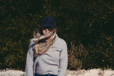 Portrait of woman wearing warm clothing while standing against plants