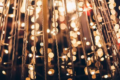 Close-up of illuminated light bulb hanging at night