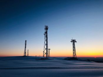 Low angle view of electricity pylon against clear sky during sunset