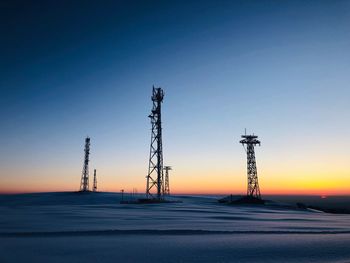 Silhouette of power transmission towers at sunset in winter