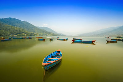 View of boats moored in lake against sky