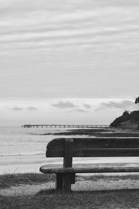 Bench by sea against sky