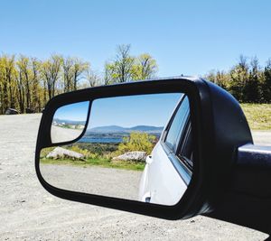 Close-up of side-view mirror against clear sky