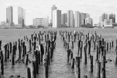 Wooden posts in sea against buildings in city