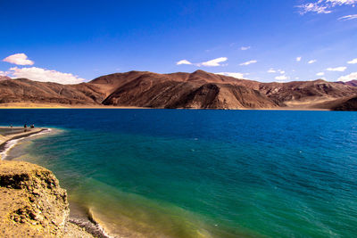 Scenic view of sea and mountains against blue sky