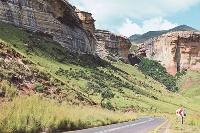 Scenic view of road by mountains against sky