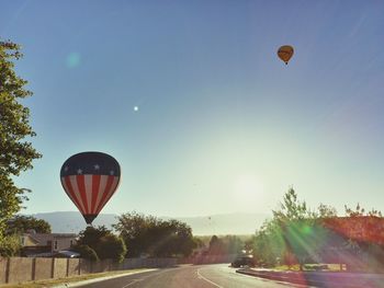 Low angle view of hot air balloon flying over road against clear sky