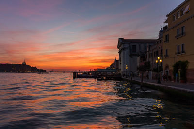 View of buildings at waterfront during sunset