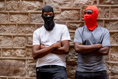 Young men wearing mask standing against wall