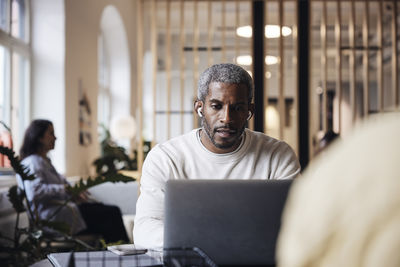 Portrait of man using laptop at cafe