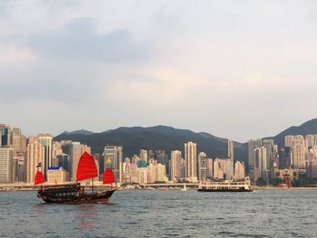 Sailboats in sea against buildings in city