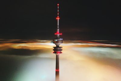 Communications tower in city against sky at night