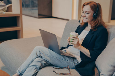 Young woman using mobile phone while sitting on sofa at home