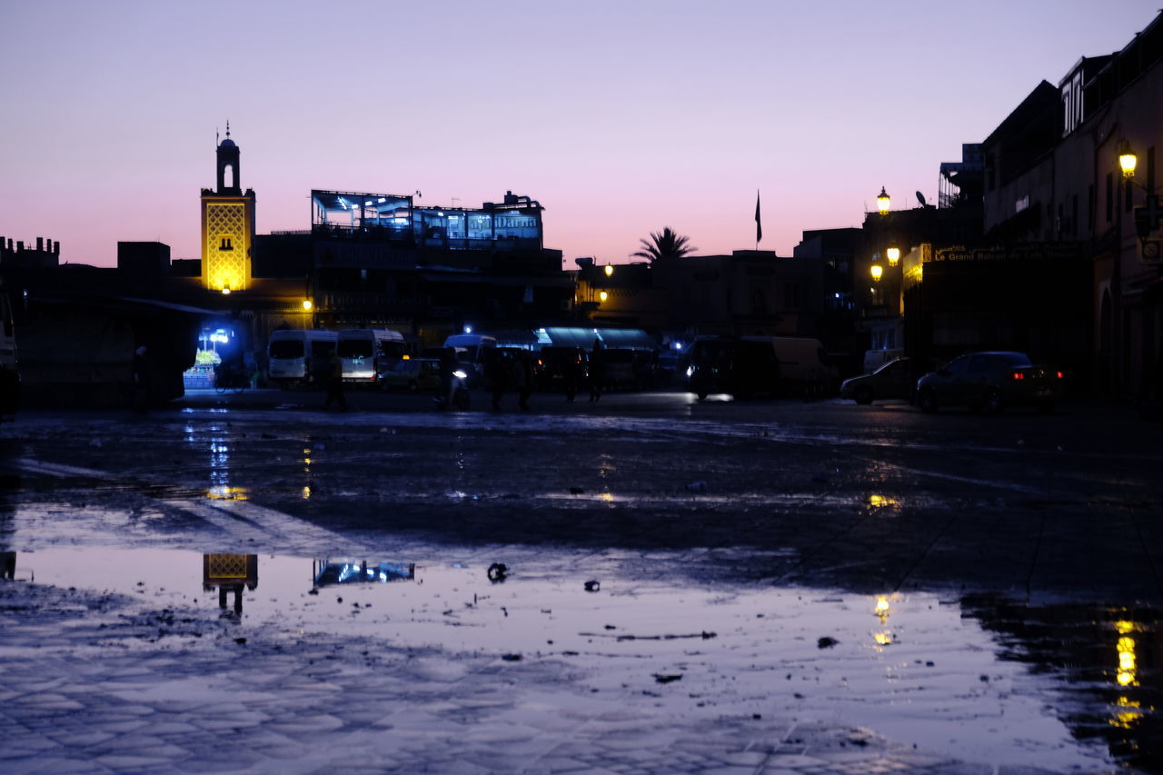 ILLUMINATED STREET BY BUILDINGS AGAINST SKY AT DUSK