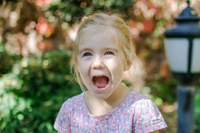 Portrait of a happy little girl with blond hair and blue eyes, mouth wide open