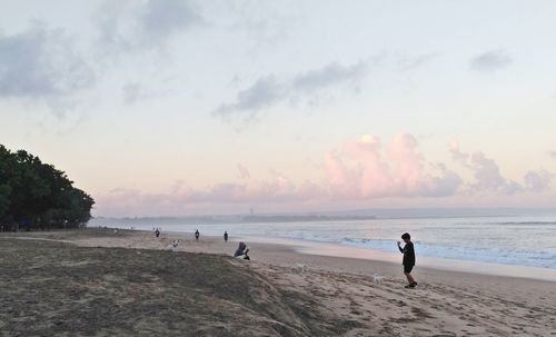 People on beach against sky during sunset