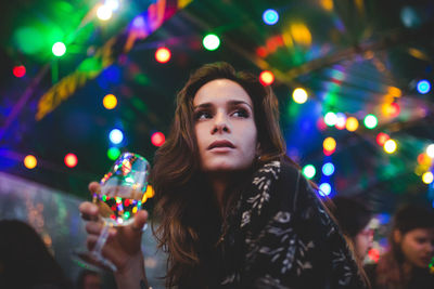 Portrait of young woman looking at illuminated camera