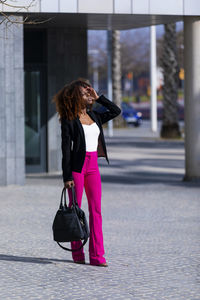 Woman standing on footpath in city